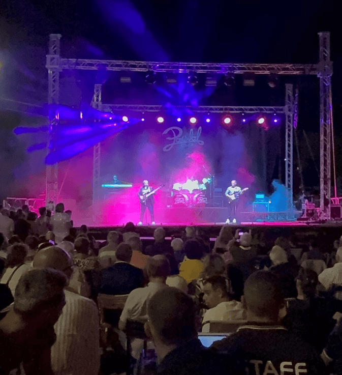 Home 7 Concerto dal vivo con band sul palco di Pagano, pubblico entusiasta.